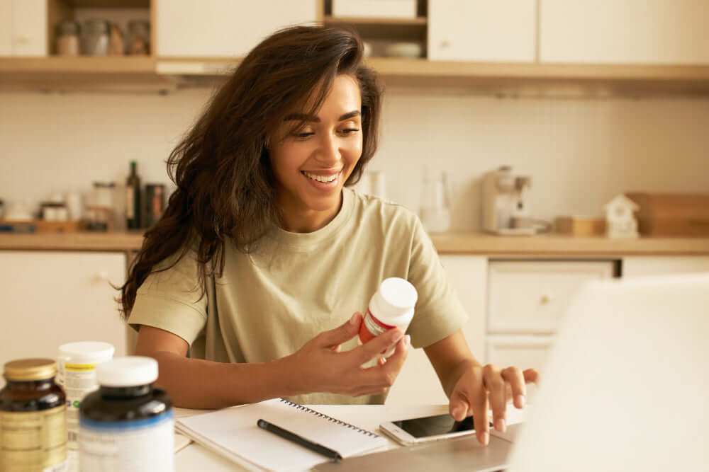 Woman smiling while holding a Zororra Plant-Based Wellness Supplements bottle.