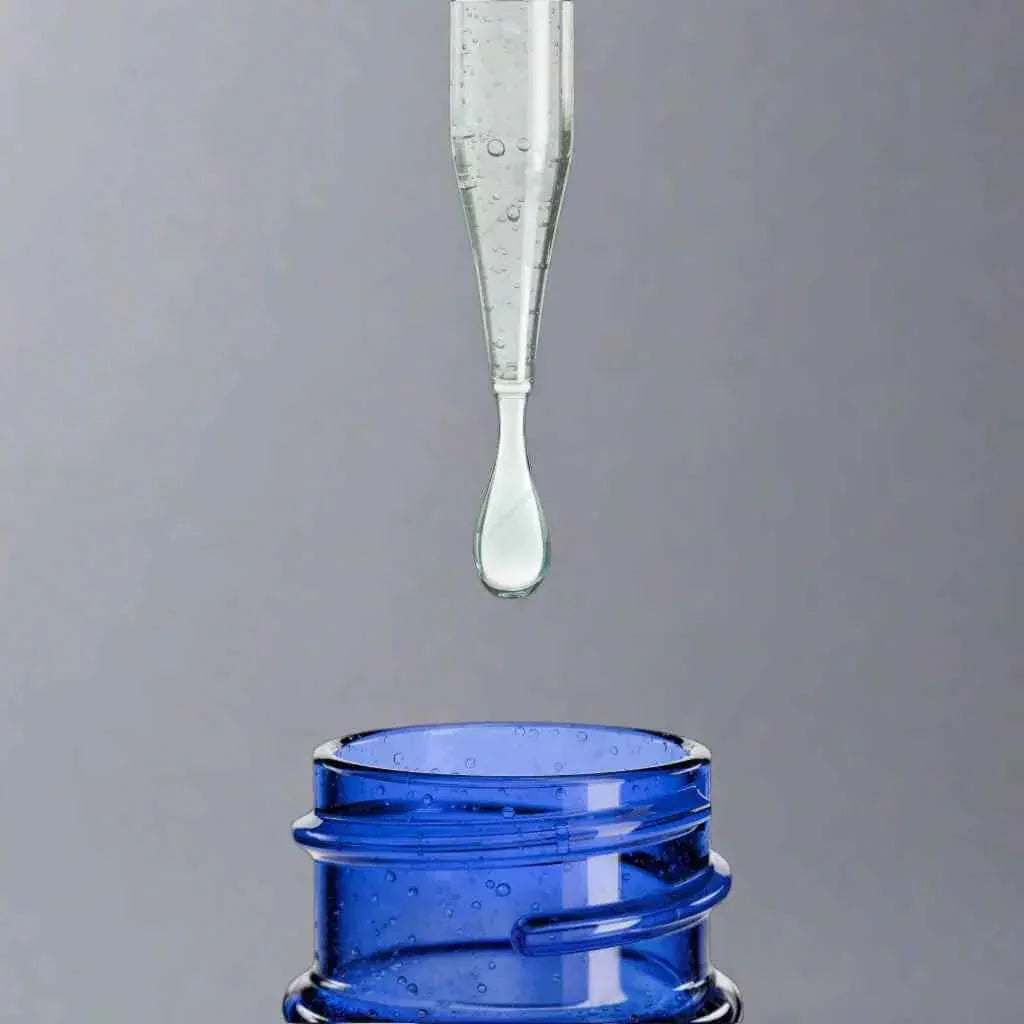 Clear liquid dropper dispensing supplement into blue glass bottle