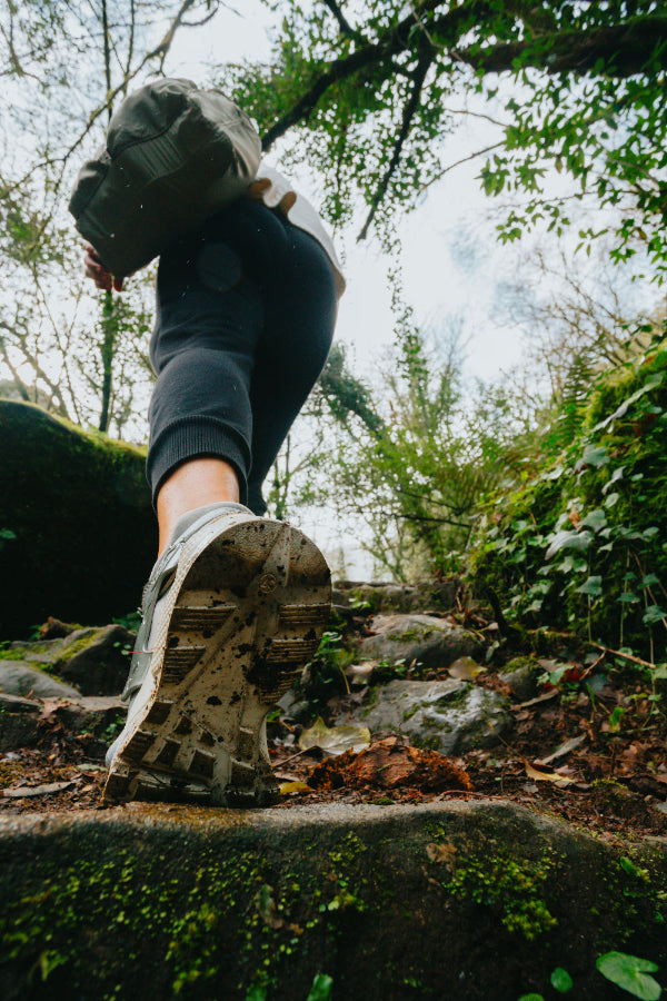 Person hiking on a rocky trail with greenery in the background